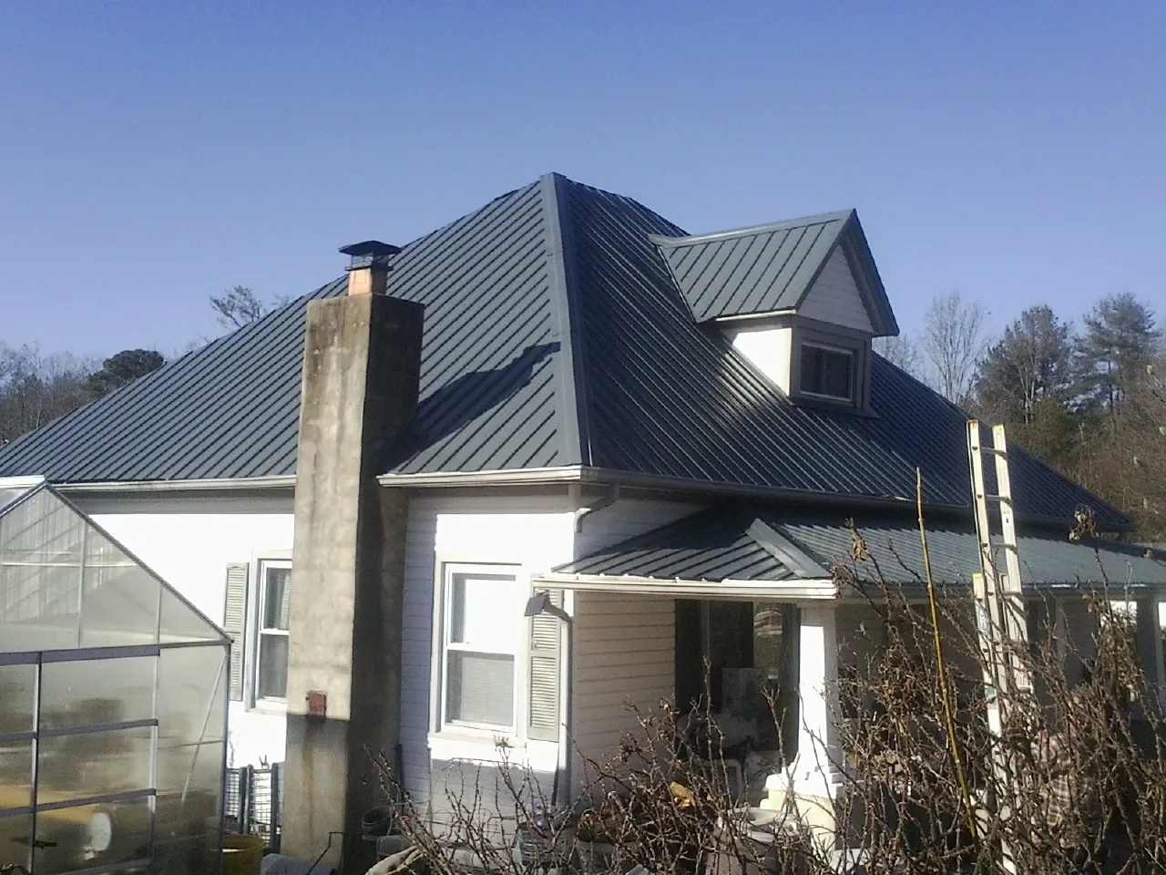 Dark blue standing seam metal roof on a white farmhouse with dormer — Slate & Tile Roof Repair by Roofing Brothers in Fair Bluff