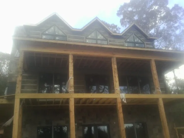 Dormers and porch framing on a large log home under construction — Roof Coating work by our crew in Fair Bluff