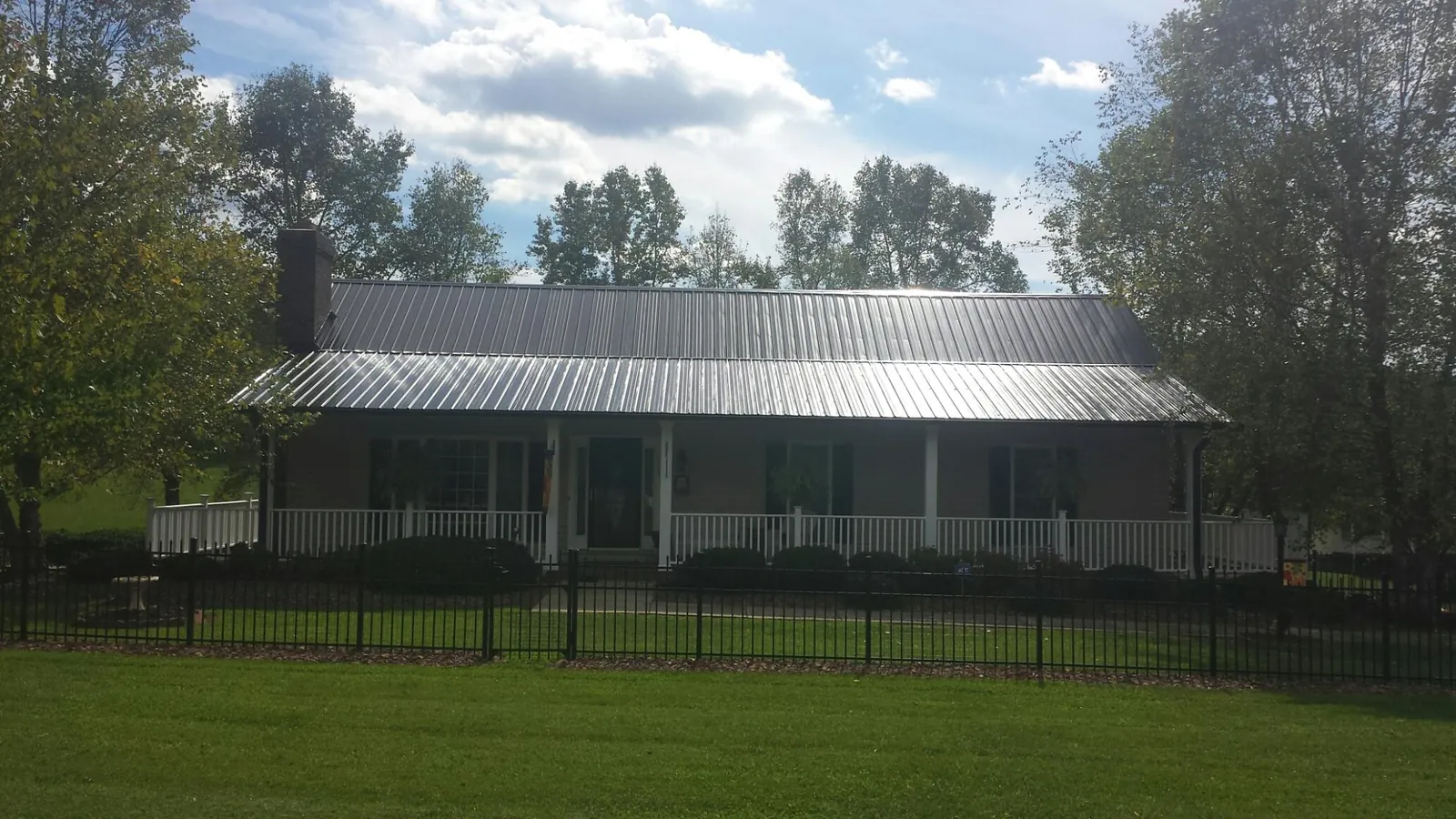 Gray metal roof on a brick ranch with a full width front porch — Gutter Guard Installation work by our crew in Fair Bluff